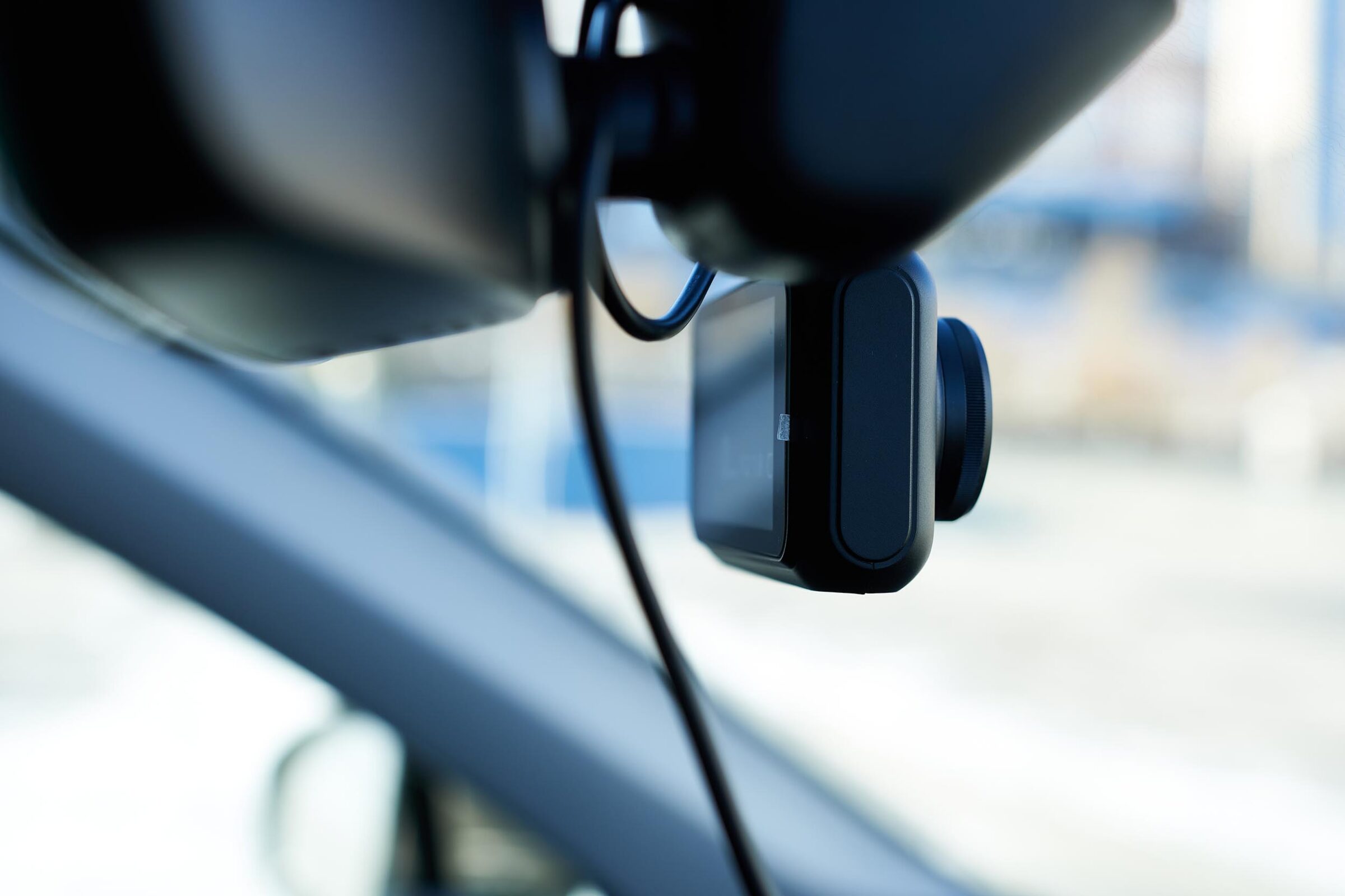 A close-up of a dash cam in a modern car against a blurred background.