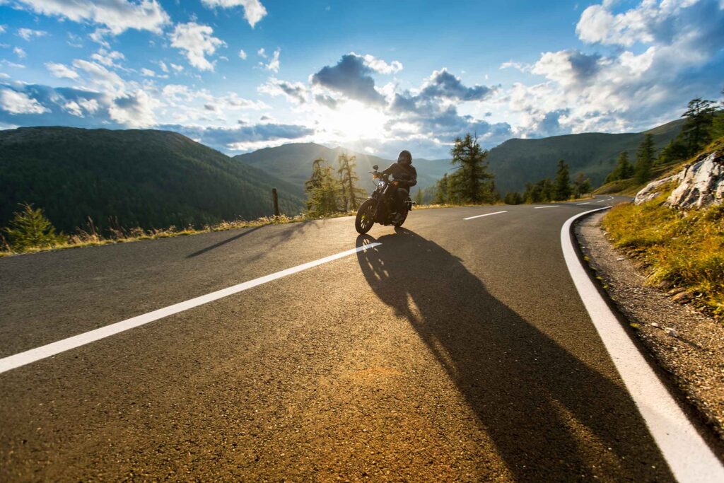 Motorbiker riding in beautiful sunset with dramatic sky.