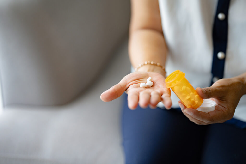 woman taking medicine from pill bottle
